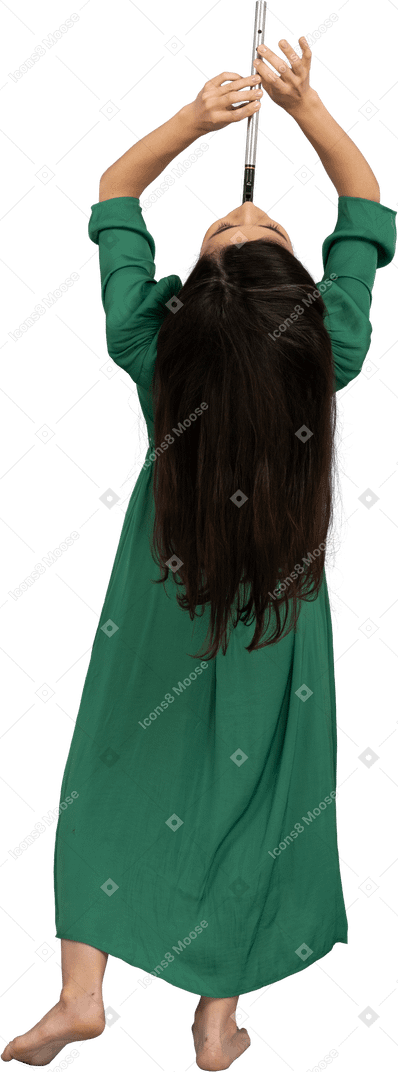 Vista posteriore di una giovane donna in abito verde che suona il flauto mentre si appoggia indietro