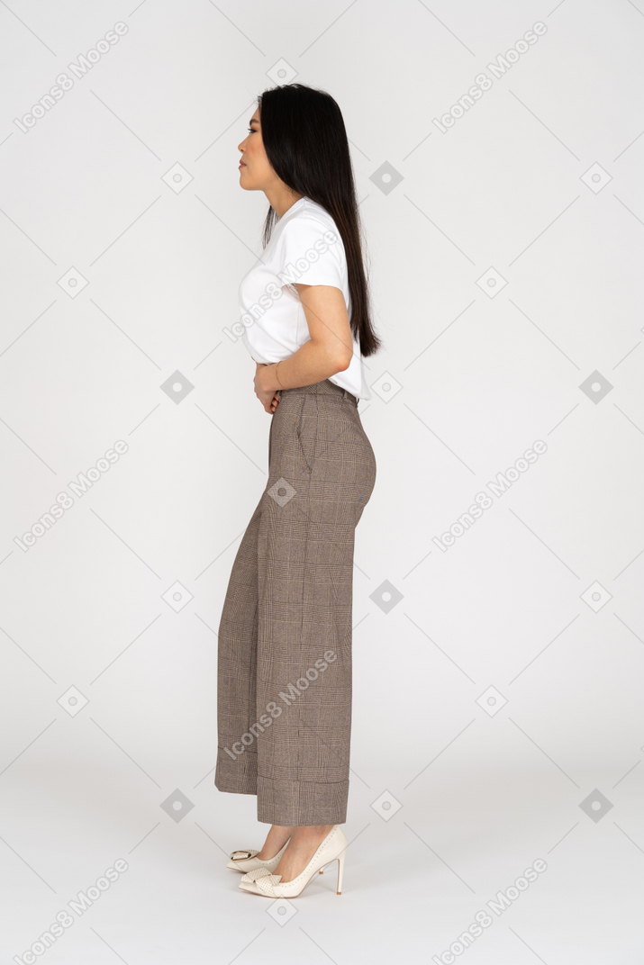 Side view of a young lady in breeches and t-shirt touching her stomach