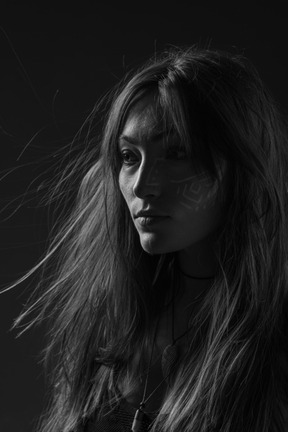 Noir three-quarter portrait of a young female with ethnic facial art and messy hair