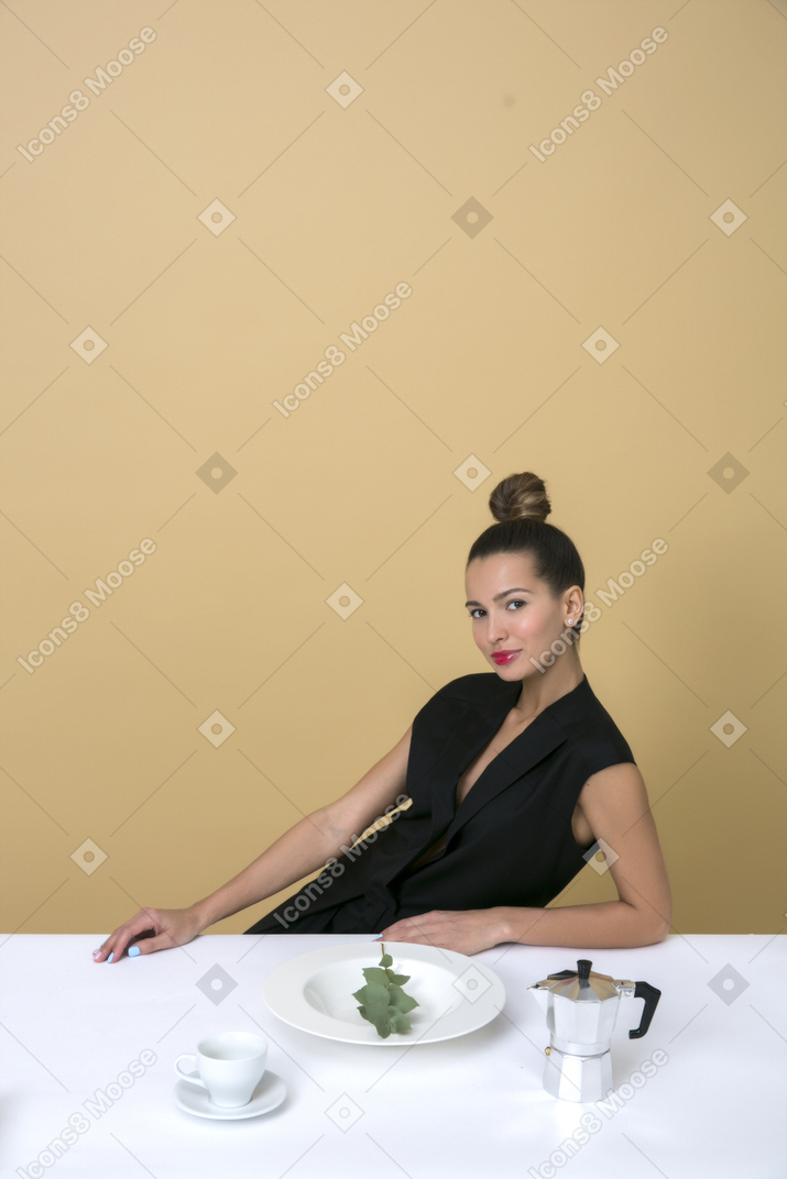 Elegante mujer joven sentada en la mesa