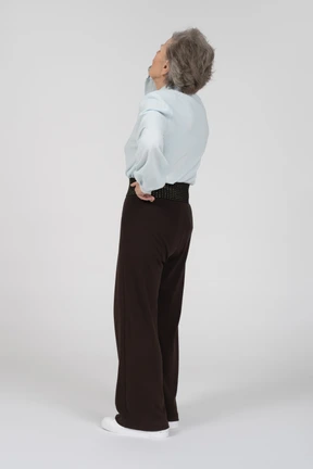 Three-quarter back view of an old woman tilting her head back