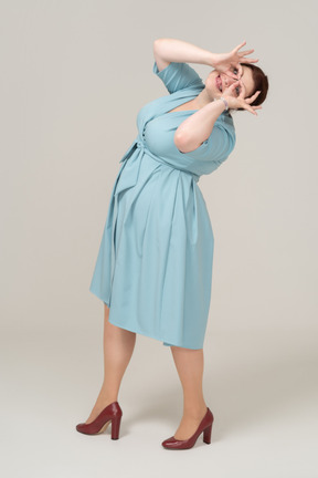 Side view of a woman in blue dress looking through imaginary binoculars