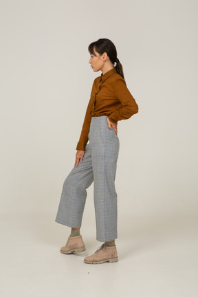 Side view of a young asian female in breeches and blouse putting hand on hip
