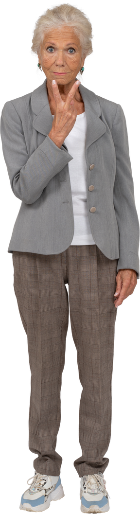 Vista frontal de una anciana en traje mostrando signo v