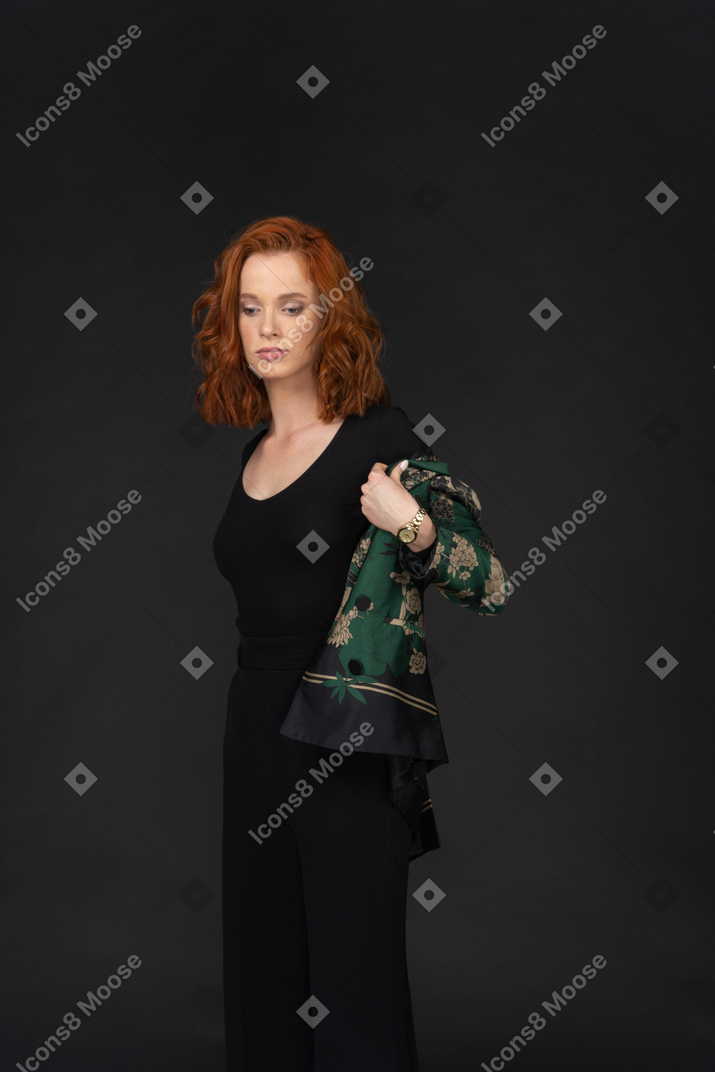 Young woman in black pants and top taking jacket off