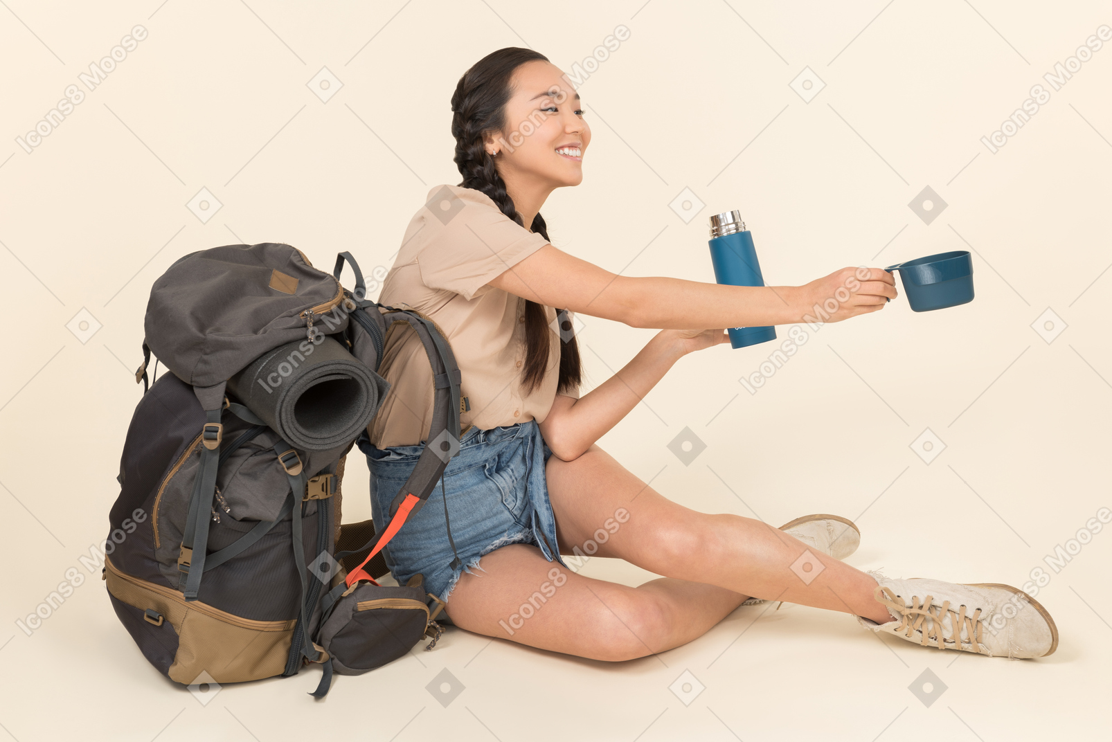 Joven mujer asiática sentada cerca de mochila y manejo de termo