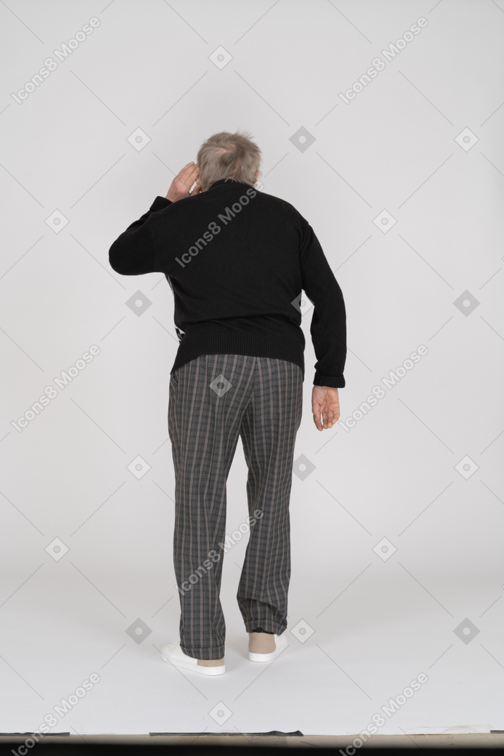 Back view of old man holding hand near his ear