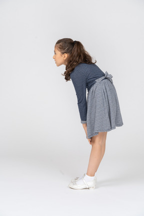 Vista lateral de una niña encorvada con las manos en las rodillas