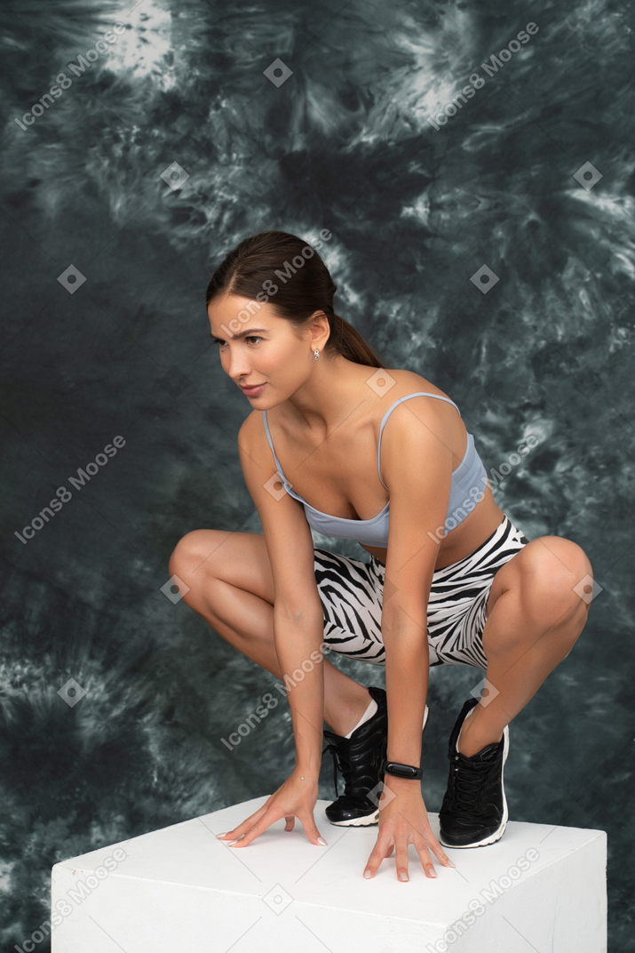 Una atleta femenina sentada a cuatro patas mirando a un lado