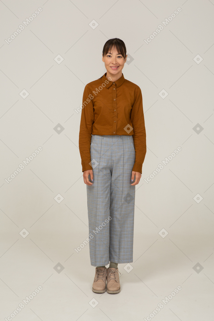 Front view of a smiling young asian female in breeches and blouse standing still