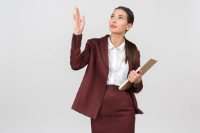 Atraente mulher formalmente vestida com uma prancheta apontando para algo