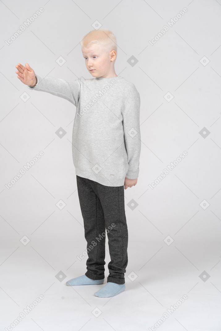 Niño pequeño de pie con el brazo extendido