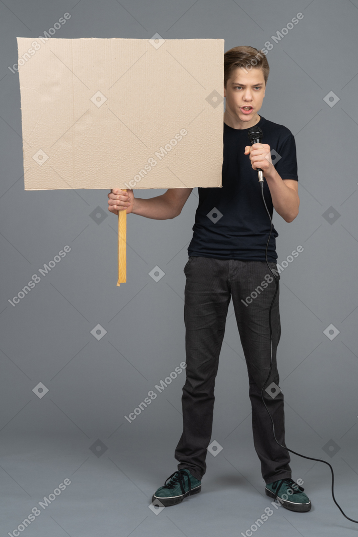 Giovane uomo che parla in un microfono e in possesso di un poster