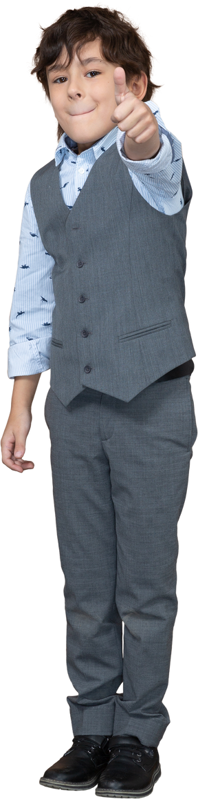 Vista frontal de un niño con traje gris que muestra el pulgar hacia arriba
