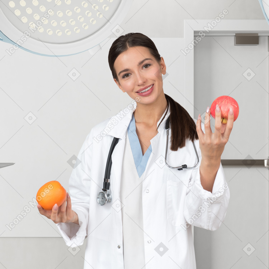 A female doctor holding an apple and an orange in a hospital