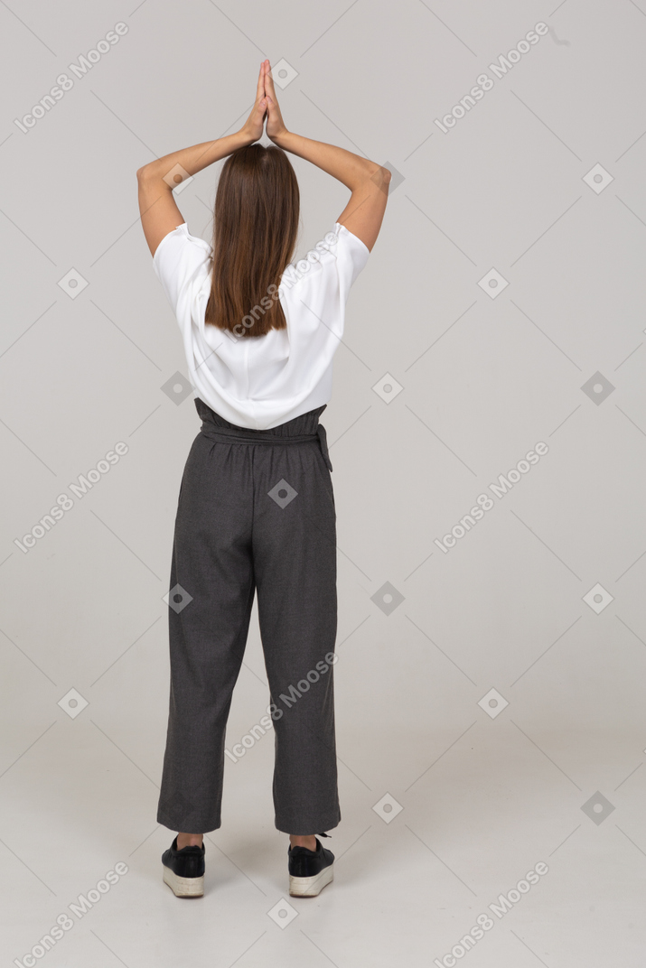 一位身着办公室服装的年轻女士双手举过头顶的背影