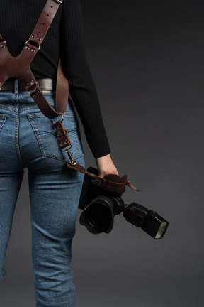 Woman standing backwards while holding a camera at shoulder level