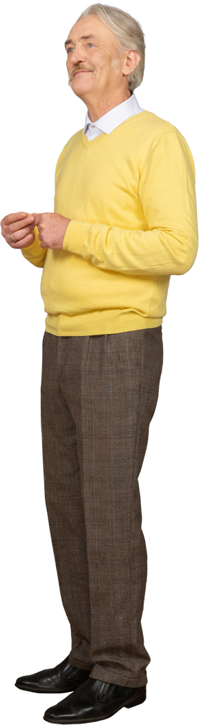 Vista de três quartos de um homem velho em um pulôver amarelo juntando as mãos e olhando para o lado