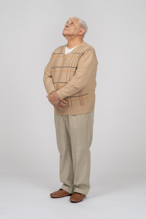 Front view of an old man in casual clothes looking up