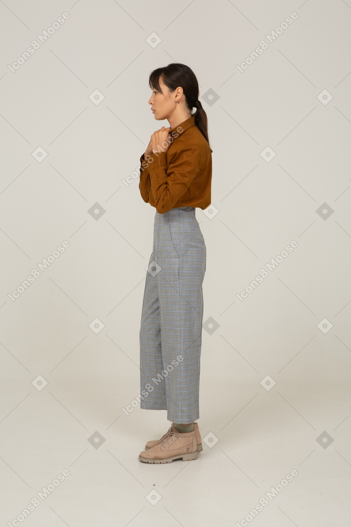 一位身着马裤和衬衫的年轻亚洲女性手牵手的侧视图