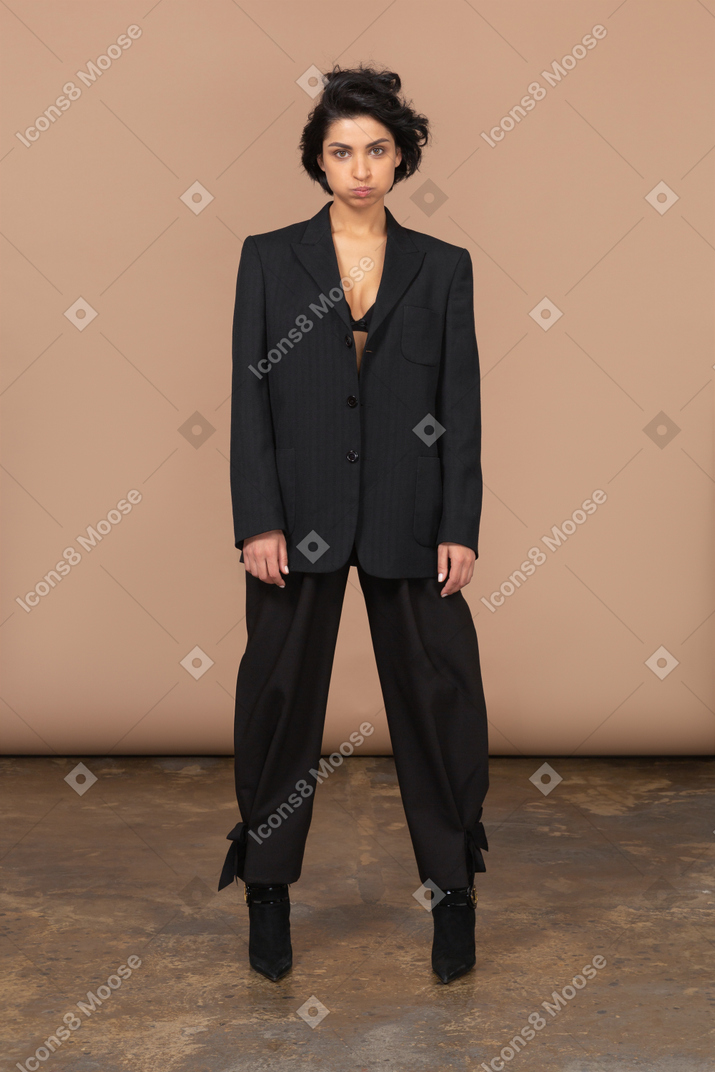 Vorderansicht einer posierenden geschäftsfrau in einem schwarzen anzug, der kamera betrachtet