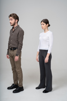 Three-quarter view of a surprised young couple in office clothing raising brows