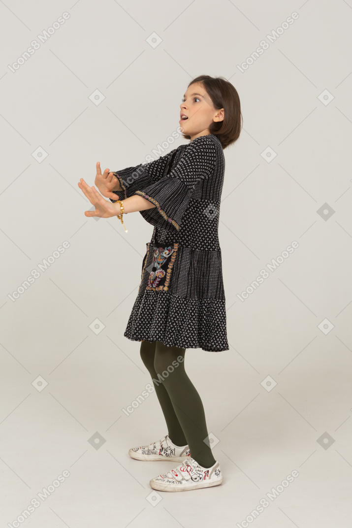 Vista de tres cuartos de una niña vestida extendiendo sus brazos