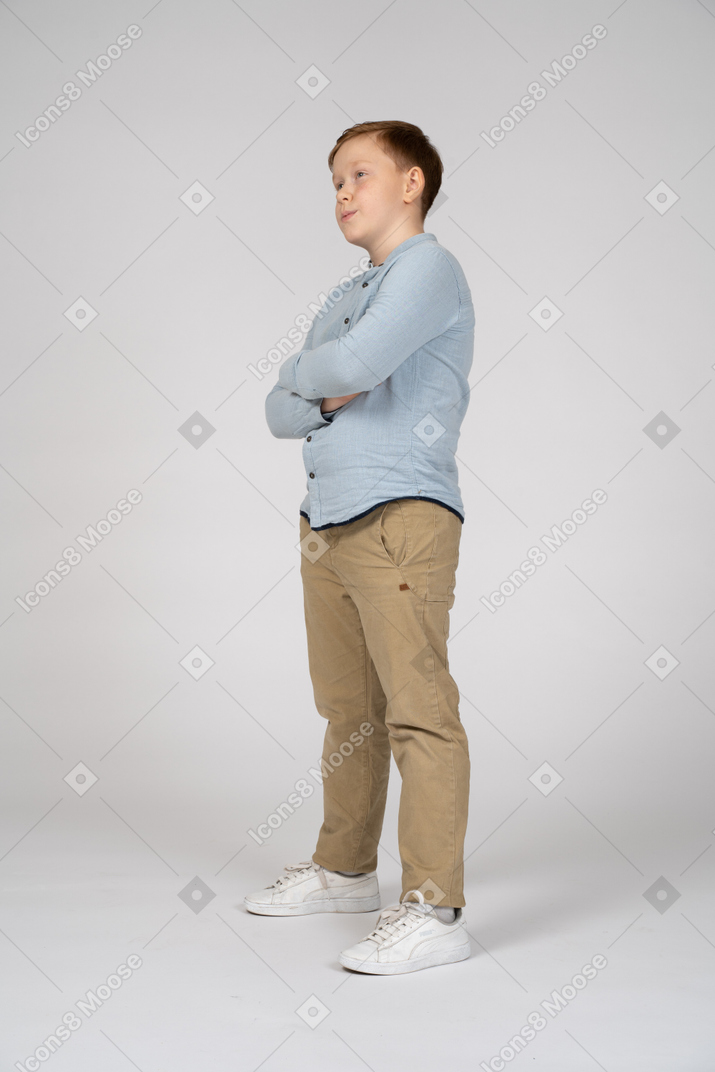 Side view of a cute boy standing with crossed arms
