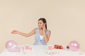 Contente jovem mulher asiática sentado à mesa de aniversário