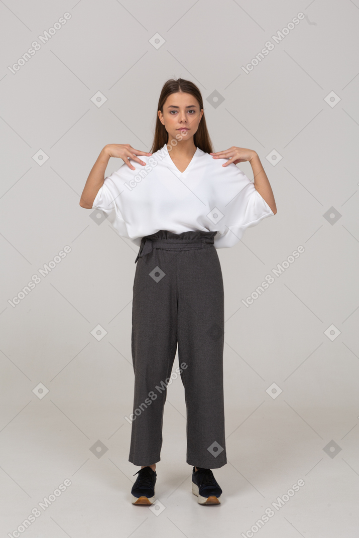 Front view of a young lady in office clothing touching her shoulders