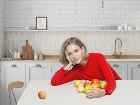 Mujer hermosa joven en sudadera roja sentada en la cocina