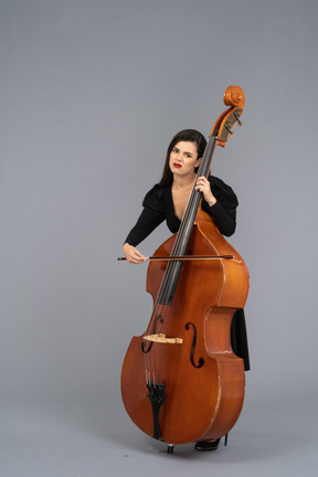 Three-quarter view of a bored young woman playing the double-bass