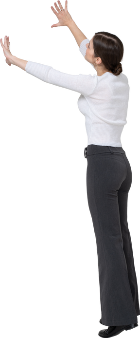 Vista laterale di una donna in abiti casual in piedi con le braccia alzate