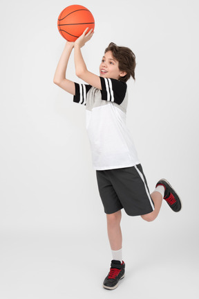 Niño moviendo y lanzando una pelota de baloncesto