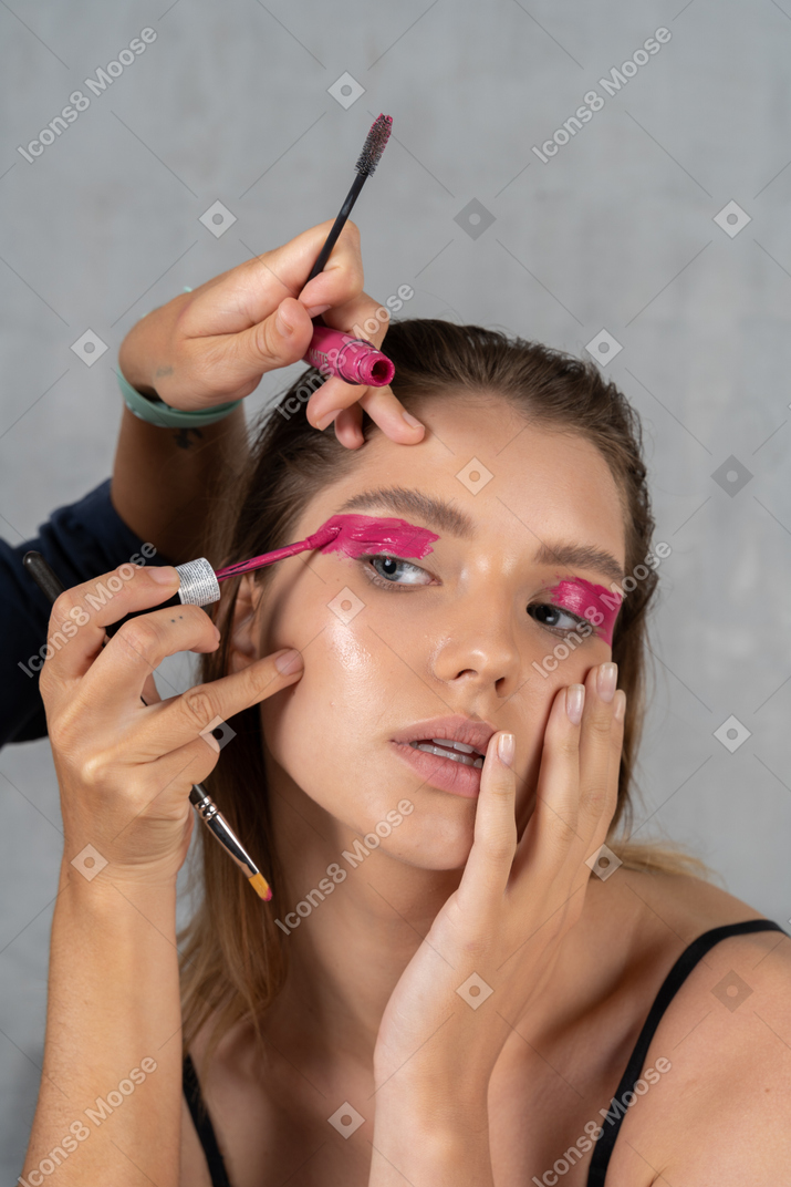 Close-up of a young woman having her make-up done