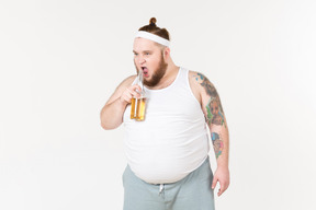 Um homem gordo em sportswear vai beber um pouco de cerveja