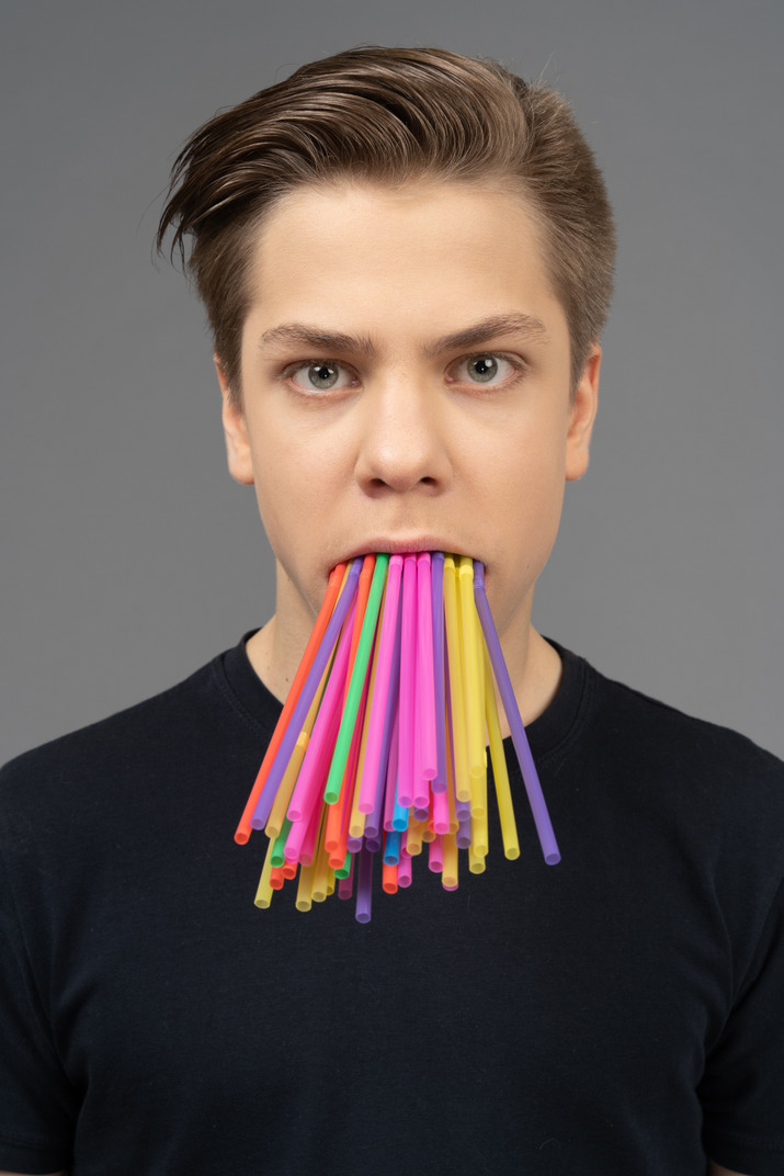 Man holding plastic straws in his mouth looking at camera