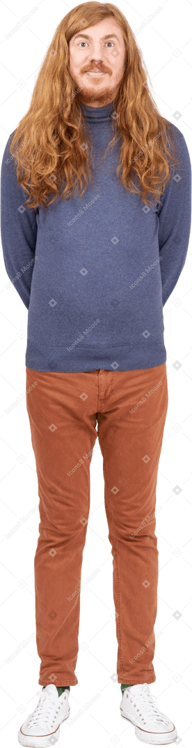 Vue de face d'un jeune homme en vêtements décontractés debout avec les mains derrière le dos