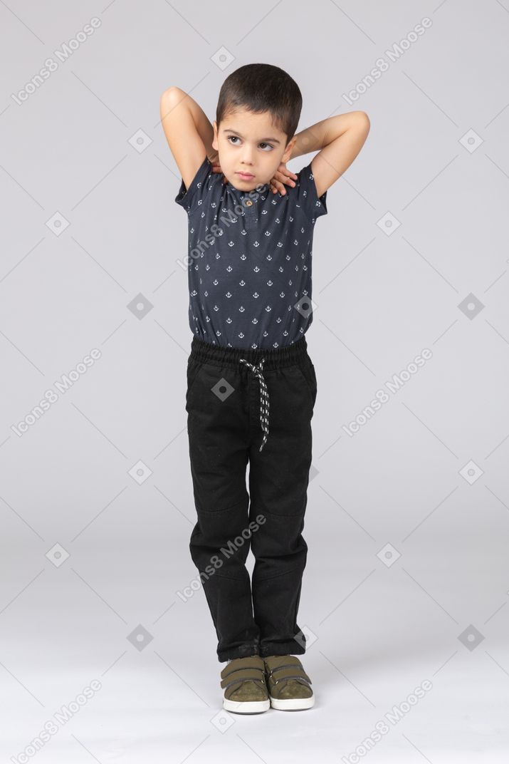 一个可爱的男孩双手放在头后摆姿势的前视图
