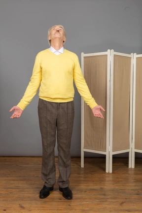 Front view of an old man outspreading hands and looking up