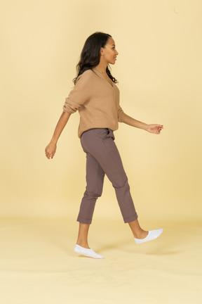 Side view of a dark-skinned walking young female