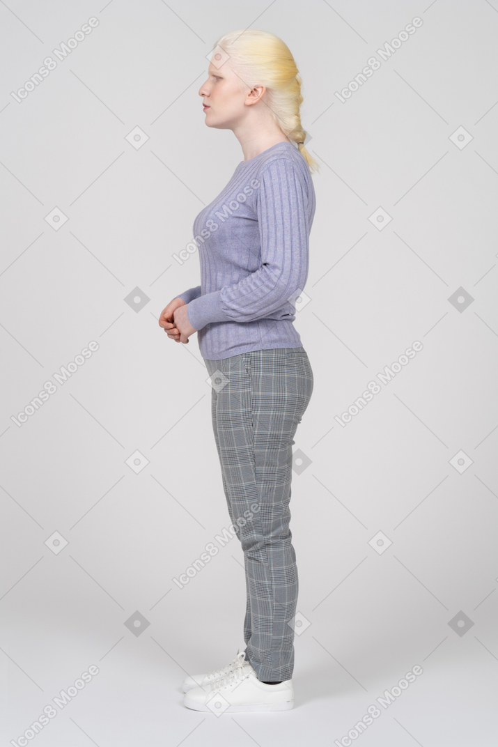 Side view of a young woman standing with her hands folded