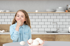 A little girl standing in front of a bowl of eggs