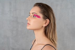 Tiro en la cabeza de una hermosa mujer joven con maquillaje de ojos de color rosa brillante