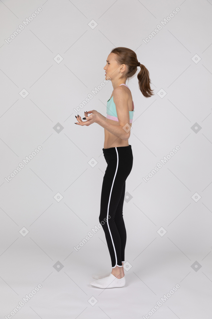 Vista lateral de uma adolescente descontente em roupas esportivas, levantando as mãos
