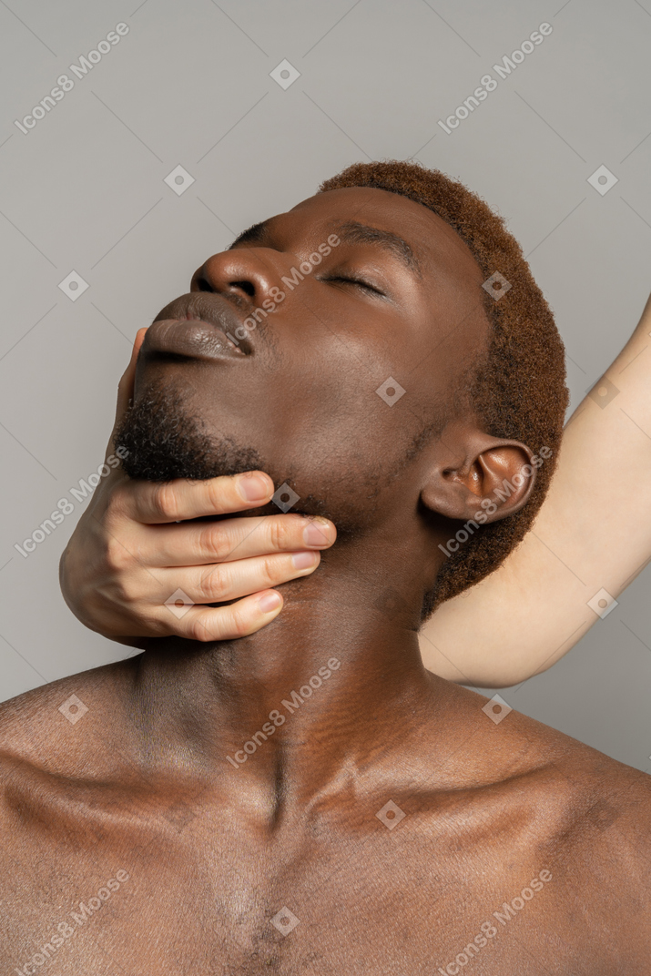 White hand holding neck of a young black man