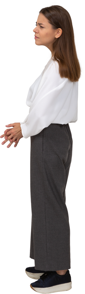 Side view of a confused young lady in office clothing holding hands together