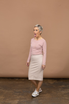 Vista lateral de uma mulher com roupas casuais mostrando a língua