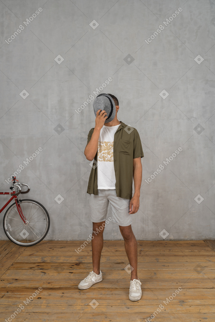 Man in casual clothes covering his face with a hat