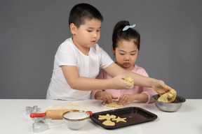 Menino ensinando sua irmã a assar biscoitos